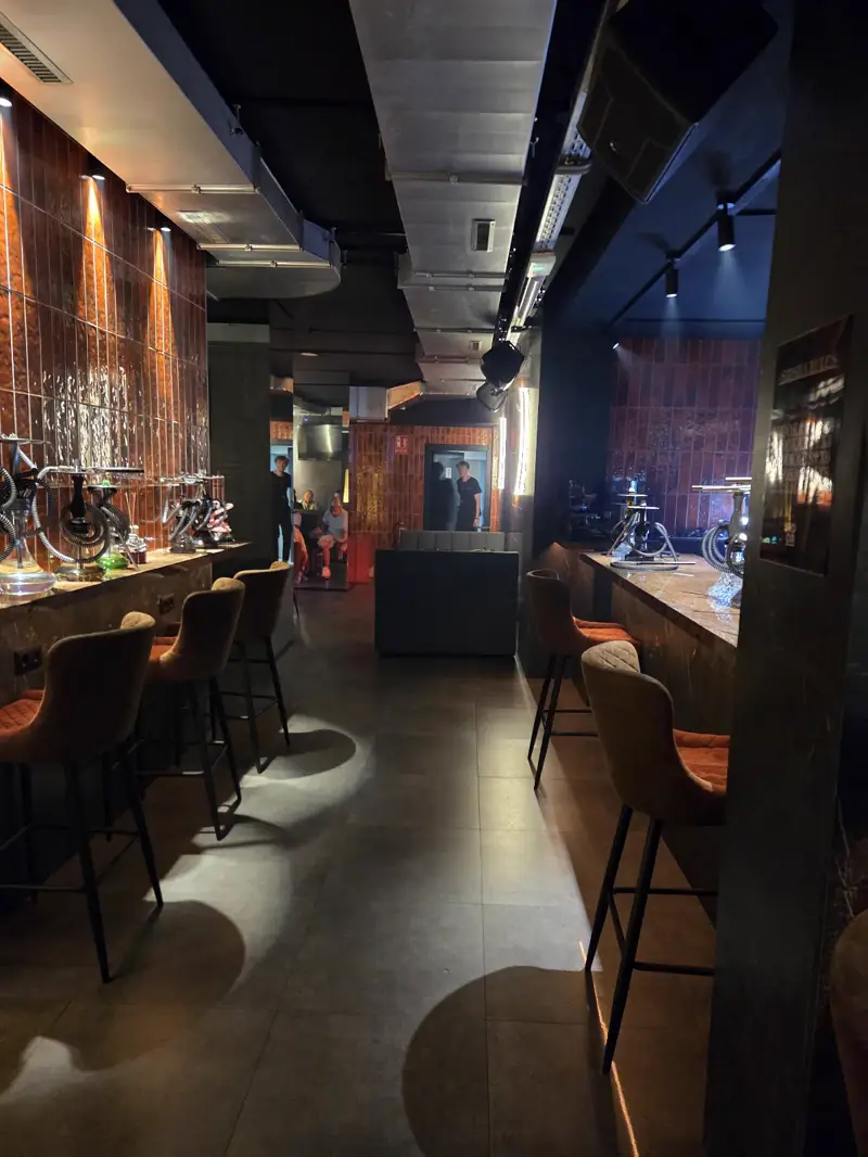 Sala de NOOR, shisha lounge en Valencia, con barra de azulejo cobrizo, taburetes y cachimbas