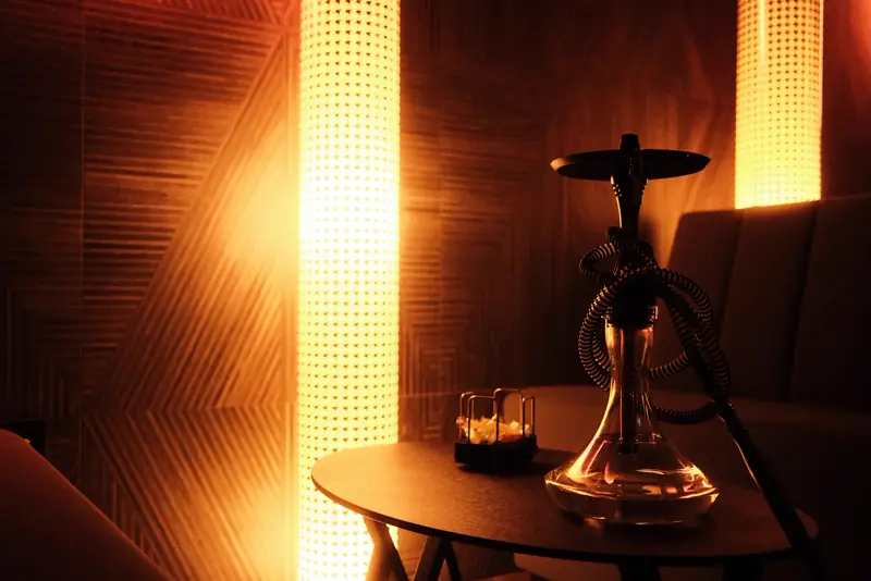 Rincón con cachimba y columna de luz cálida en NOOR Lounge